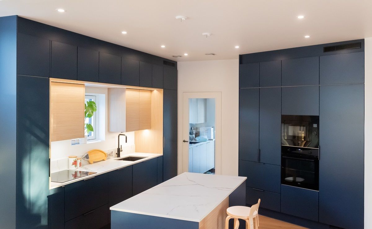 The ceiling spotlights in the open kitchen are arranged in a circle in front of the cabinets on two walls.